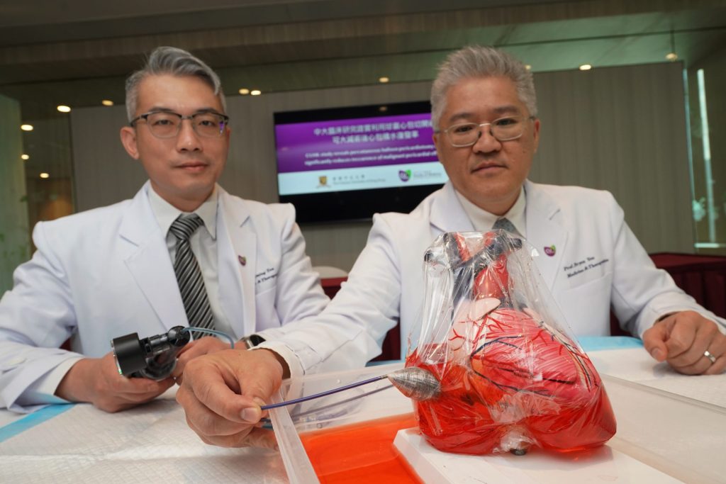 Dr. Tan and Prof. Yan seated, model heart in foreground.