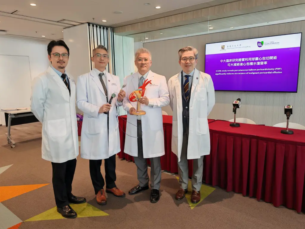 Doctors in white coats, center holds heart model. Screen text about CUHK PBP study.